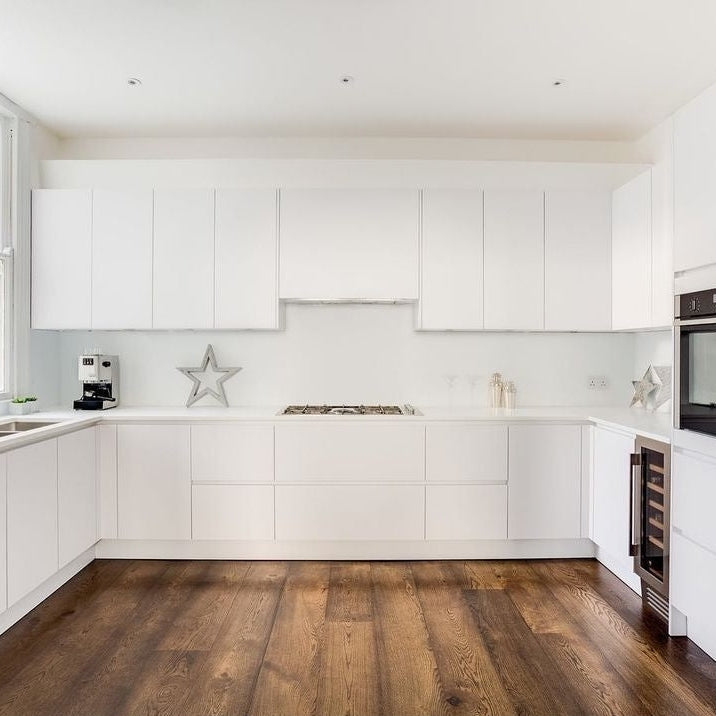 Modern white kitchen featuring a 74cm canopy built-in cooker hood in stainless steel under white cabinets with dark wood flooring.