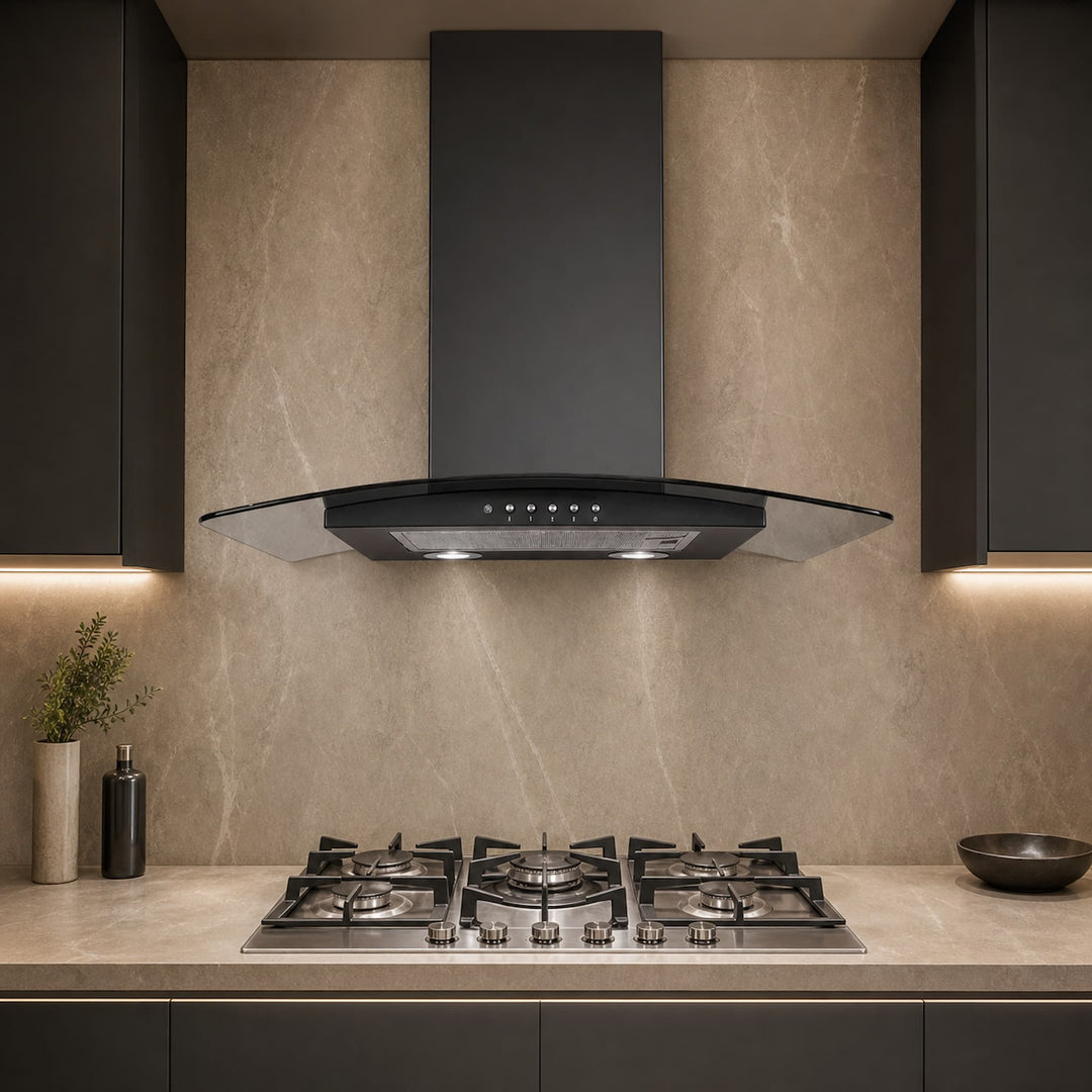 A modern kitchen scene featuring a black glass-front range hood mounted above a stainless steel gas cooktop, set against a beige stone backsplash and dark cabinetry.